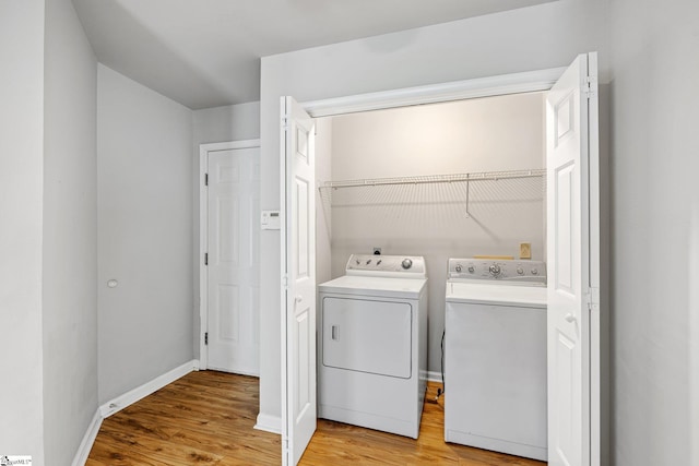 laundry room featuring baseboards, washing machine and clothes dryer, laundry area, and light wood-style flooring