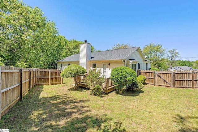 rear view of house with a yard, a fenced backyard, and a deck