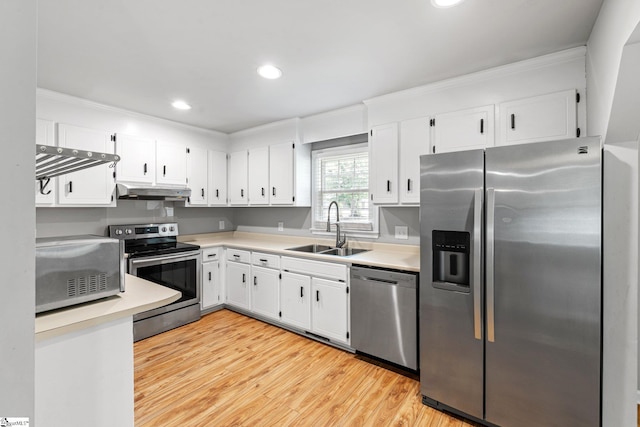 kitchen with under cabinet range hood, stainless steel appliances, a sink, crown molding, and white cabinetry