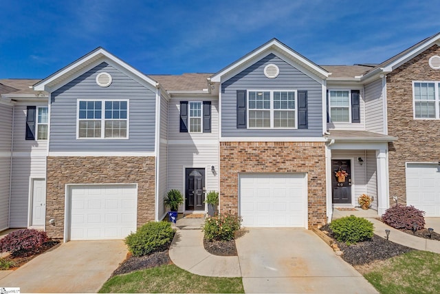 view of property with stone siding, driveway, and a garage