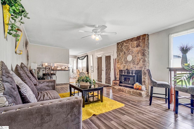 living area with a ceiling fan, wood finished floors, a textured ceiling, and ornamental molding