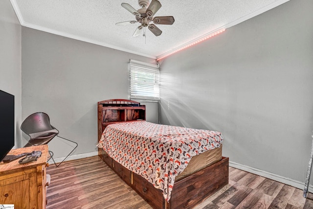 bedroom featuring wood finished floors, a textured ceiling, and crown molding