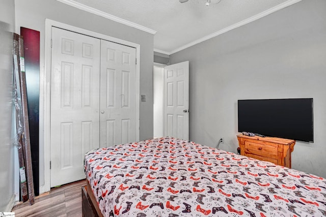 bedroom featuring crown molding, wood finished floors, a textured ceiling, and a closet