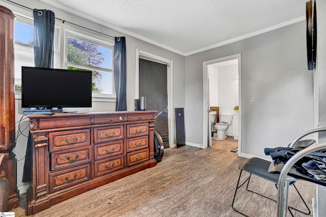 interior space featuring baseboards, crown molding, wood finished floors, and a textured ceiling