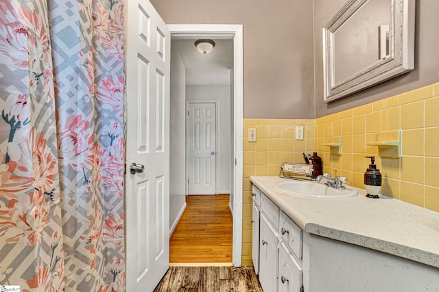bathroom featuring vanity, wood finished floors, and tile walls