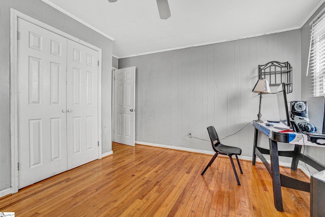 office area with baseboards, a ceiling fan, wood walls, ornamental molding, and wood-type flooring