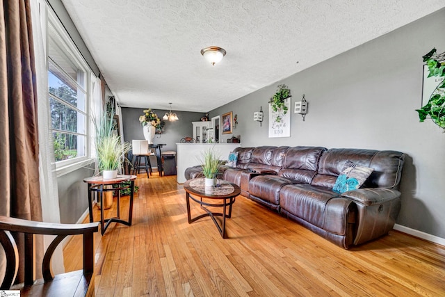 living area featuring baseboards, a textured ceiling, and light wood-style flooring