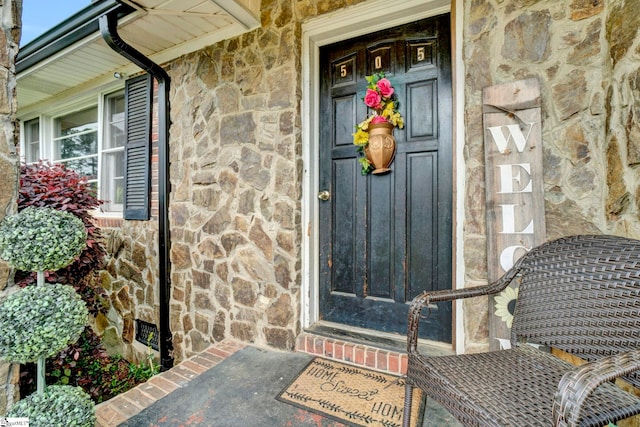 doorway to property with stone siding and a porch