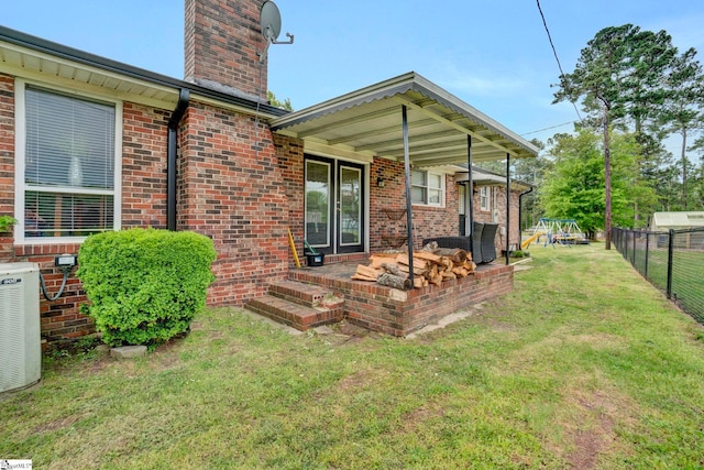 back of house with brick siding, a yard, a chimney, and fence
