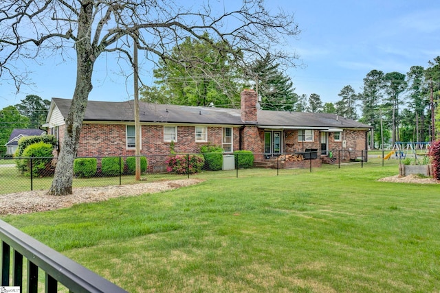 rear view of house featuring a playground, a lawn, a chimney, fence, and brick siding