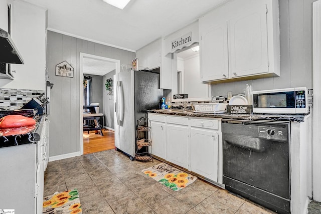 kitchen with wall chimney range hood, dark countertops, backsplash, white cabinetry, and black dishwasher