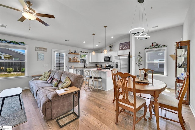 interior space with vaulted ceiling, a ceiling fan, light wood finished floors, baseboards, and visible vents
