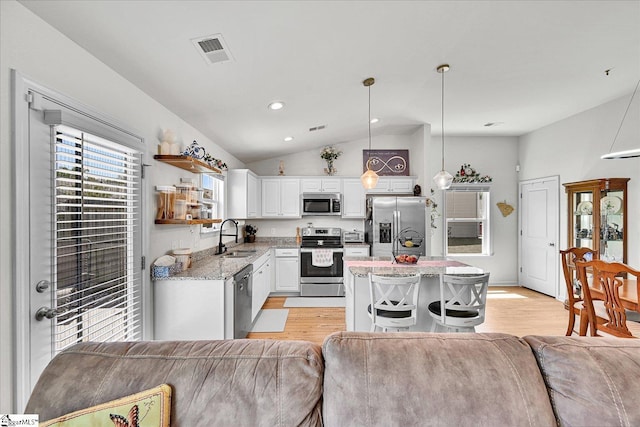 kitchen with stainless steel appliances, open floor plan, visible vents, light wood-style floors, and lofted ceiling