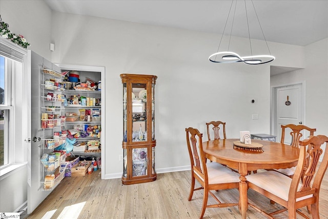 dining area with a chandelier, light wood-style flooring, and baseboards