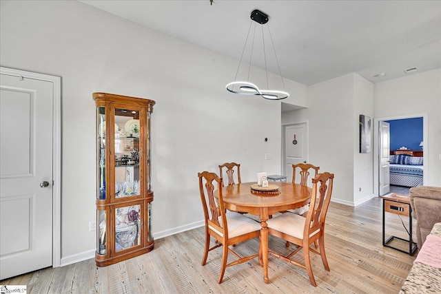 dining room featuring baseboards, a notable chandelier, and light wood-style floors