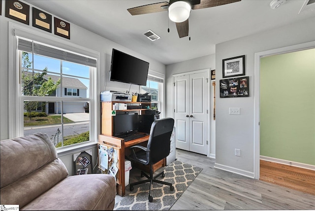office featuring light wood-style flooring, visible vents, baseboards, and ceiling fan