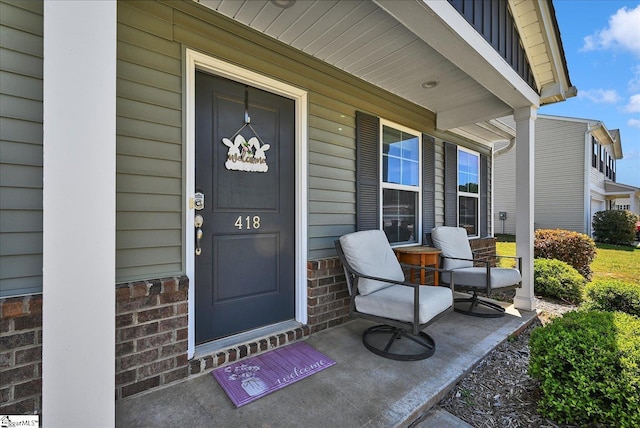 view of exterior entry with brick siding, board and batten siding, and covered porch