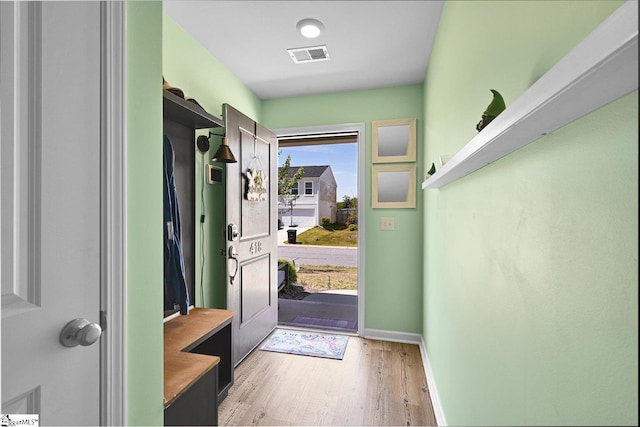 doorway to outside with light wood-style flooring, visible vents, and baseboards