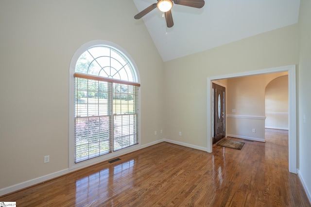 spare room with arched walkways, wood finished floors, and a healthy amount of sunlight