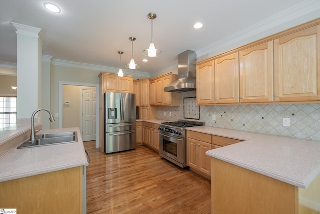 kitchen with stainless steel appliances, wall chimney range hood, light brown cabinets, a sink, and a peninsula