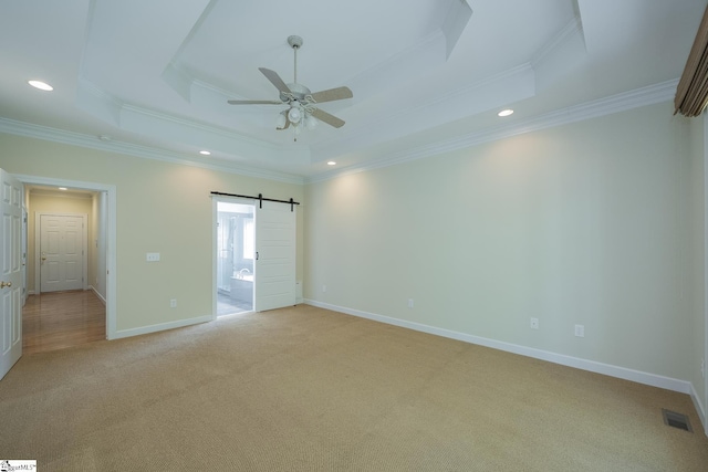 unfurnished bedroom featuring light colored carpet, crown molding, a tray ceiling, and visible vents