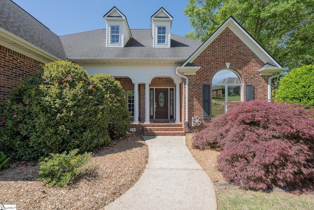 view of exterior entry featuring brick siding and roof with shingles