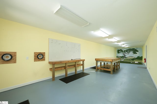 playroom with concrete floors, a workshop area, and baseboards