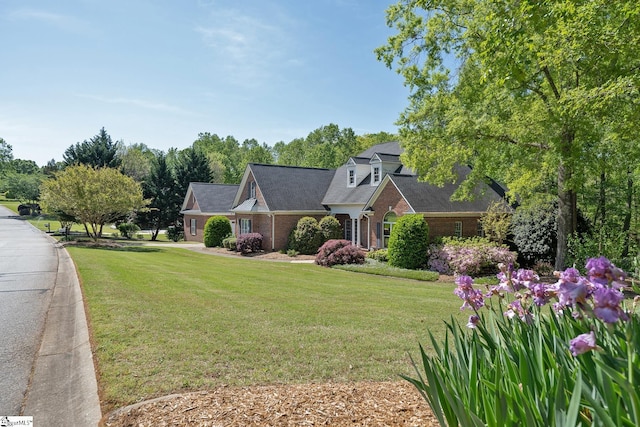 cape cod house featuring brick siding and a front yard