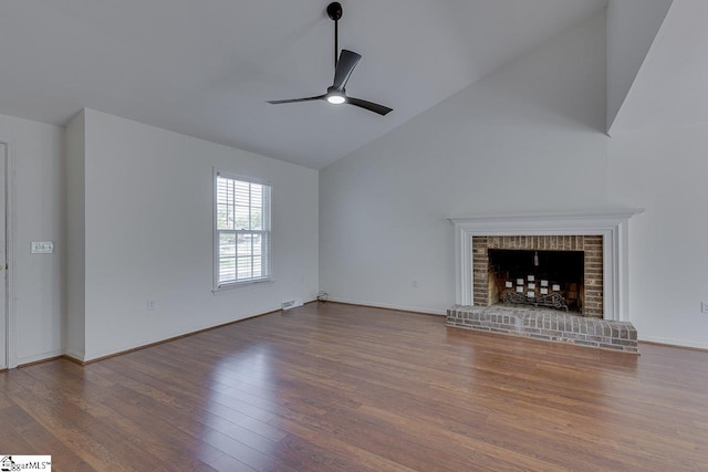 unfurnished living room featuring baseboards, a brick fireplace, wood finished floors, ceiling fan, and high vaulted ceiling