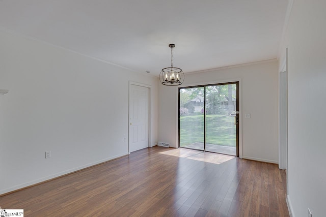 empty room with an inviting chandelier, wood finished floors, visible vents, ornamental molding, and baseboards