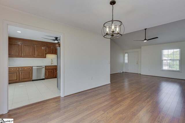 interior space with ceiling fan with notable chandelier, vaulted ceiling, and light wood-type flooring