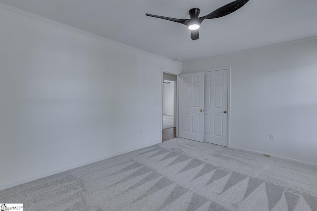 unfurnished bedroom featuring a ceiling fan, baseboards, carpet floors, and crown molding