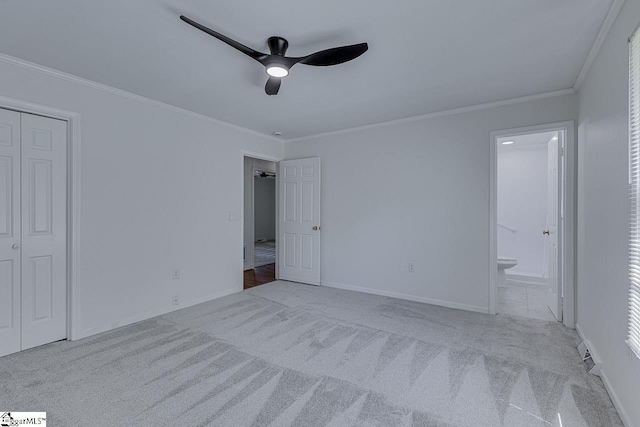 unfurnished bedroom with ensuite bathroom, baseboards, ceiling fan, crown molding, and carpet floors
