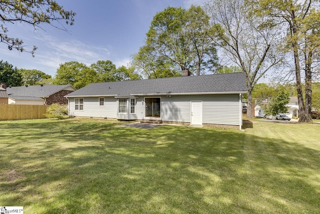back of house featuring a lawn, fence, a chimney, and entry steps