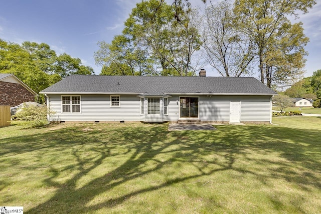 rear view of house with a yard, entry steps, roof with shingles, and a chimney