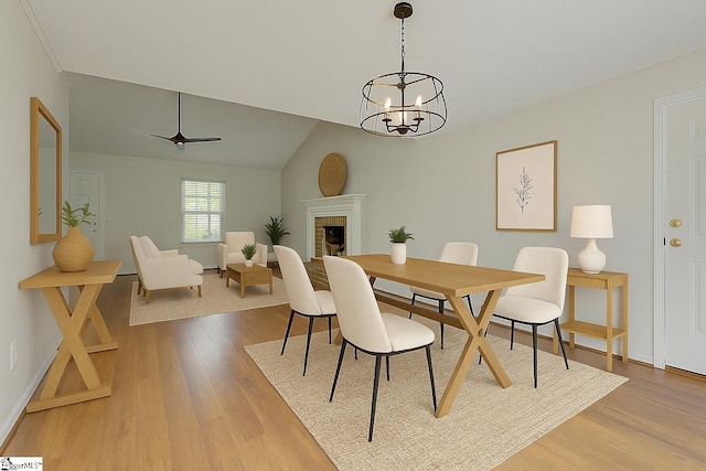 dining room featuring baseboards, a chandelier, light wood-style floors, and a fireplace