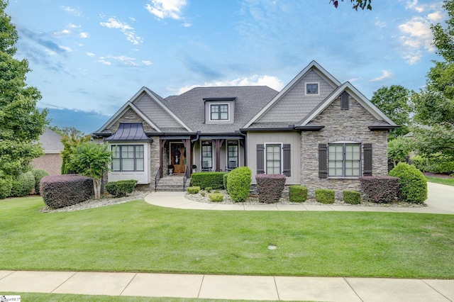 craftsman-style house featuring stone siding, a front lawn, a porch, and roof with shingles