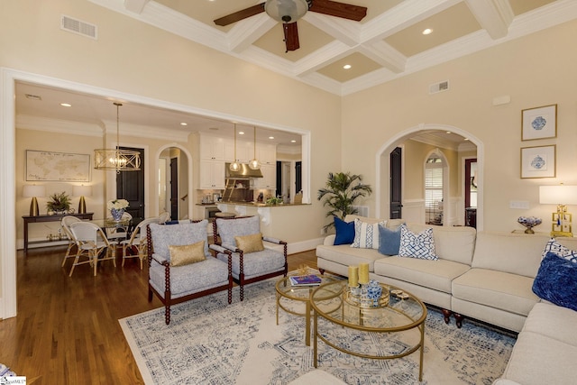 living area with arched walkways, crown molding, beamed ceiling, ceiling fan, and coffered ceiling