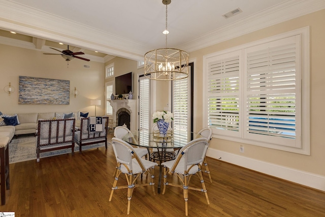 dining space featuring dark wood-type flooring, ceiling fan, ornamental molding, a chandelier, and a fireplace