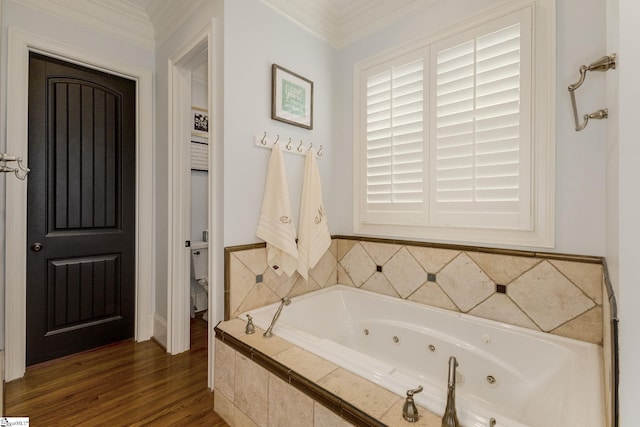 bathroom featuring a tub with jets, wood finished floors, and ornamental molding