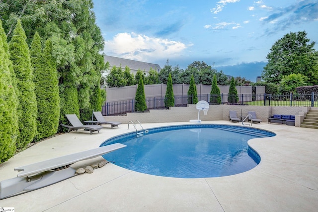 view of pool featuring a diving board, fence, and a patio area