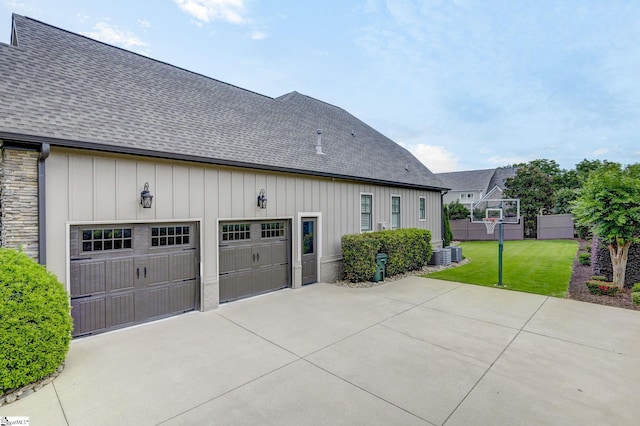 rear view of property featuring driveway, a shingled roof, board and batten siding, and a lawn