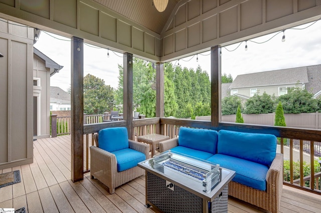 sunroom featuring an outdoor living space with a fire pit, lofted ceiling, and plenty of natural light