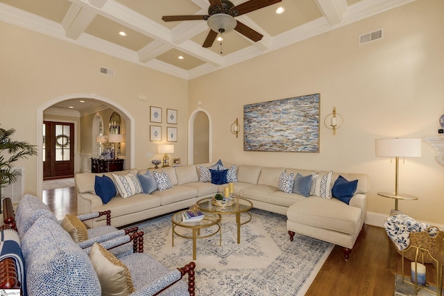 living room featuring arched walkways, coffered ceiling, ornamental molding, ceiling fan, and beam ceiling