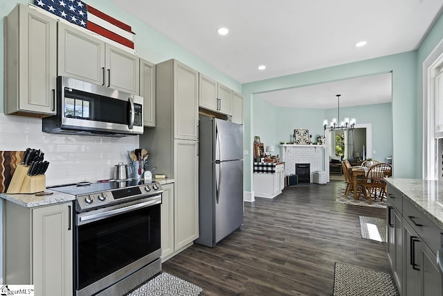 501 N Adair St, Clinton, SC 29325 - kitchen featuring dark wood-style flooring, a notable chandelier, backsplash, light stone countertops, and appliances with stainless steel finishes