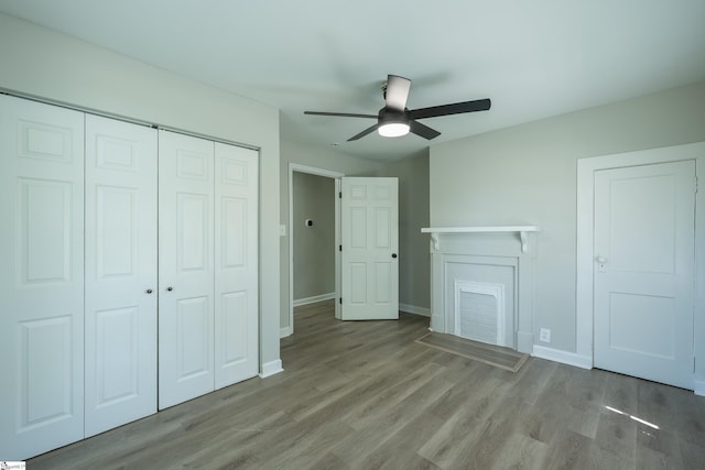 unfurnished bedroom with wood finished floors, a closet, baseboards, and ceiling fan