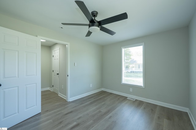 empty room with ceiling fan, baseboards, and wood finished floors