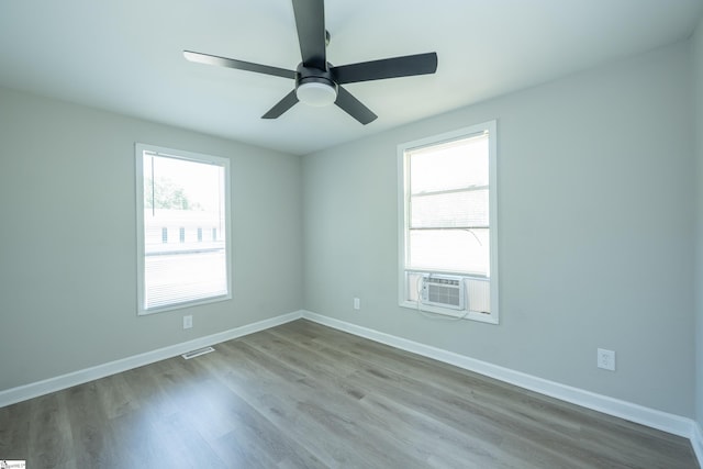 unfurnished room featuring cooling unit, baseboards, visible vents, wood finished floors, and ceiling fan
