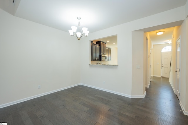 unfurnished dining area featuring baseboards, a chandelier, and dark wood-style flooring