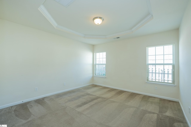 spare room featuring a tray ceiling, visible vents, ornamental molding, baseboards, and light colored carpet